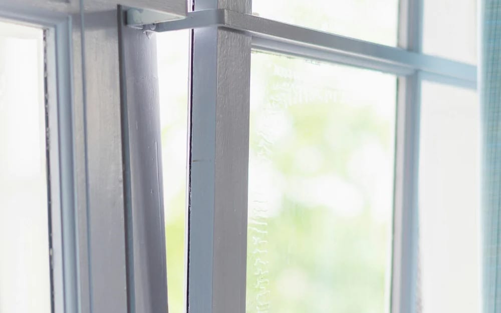 Slightly open PVC window sash in ventilation mode showing the seal and frame joint